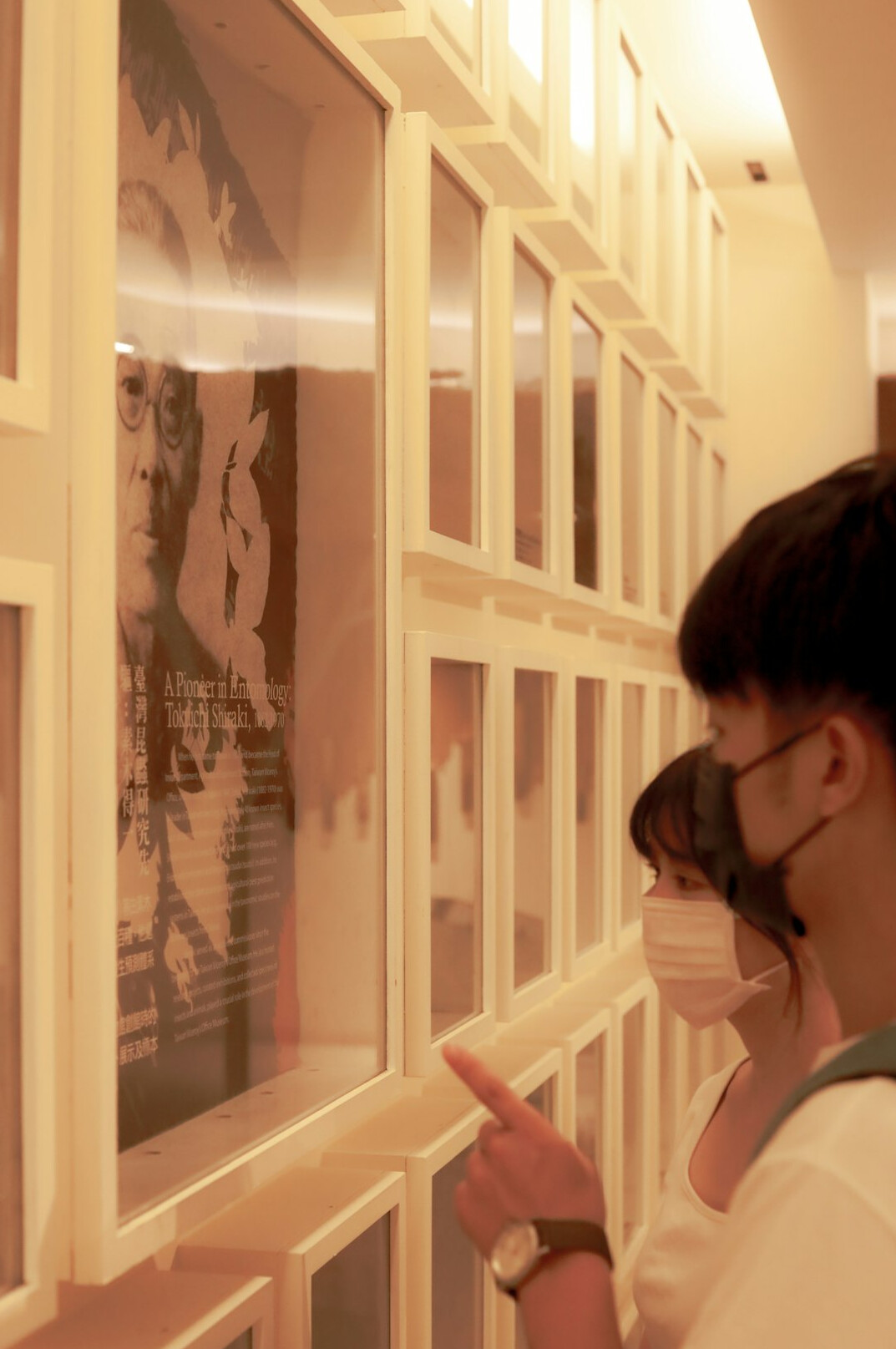 Visitors looking at framed documentary photographs in a small gallery exhibition