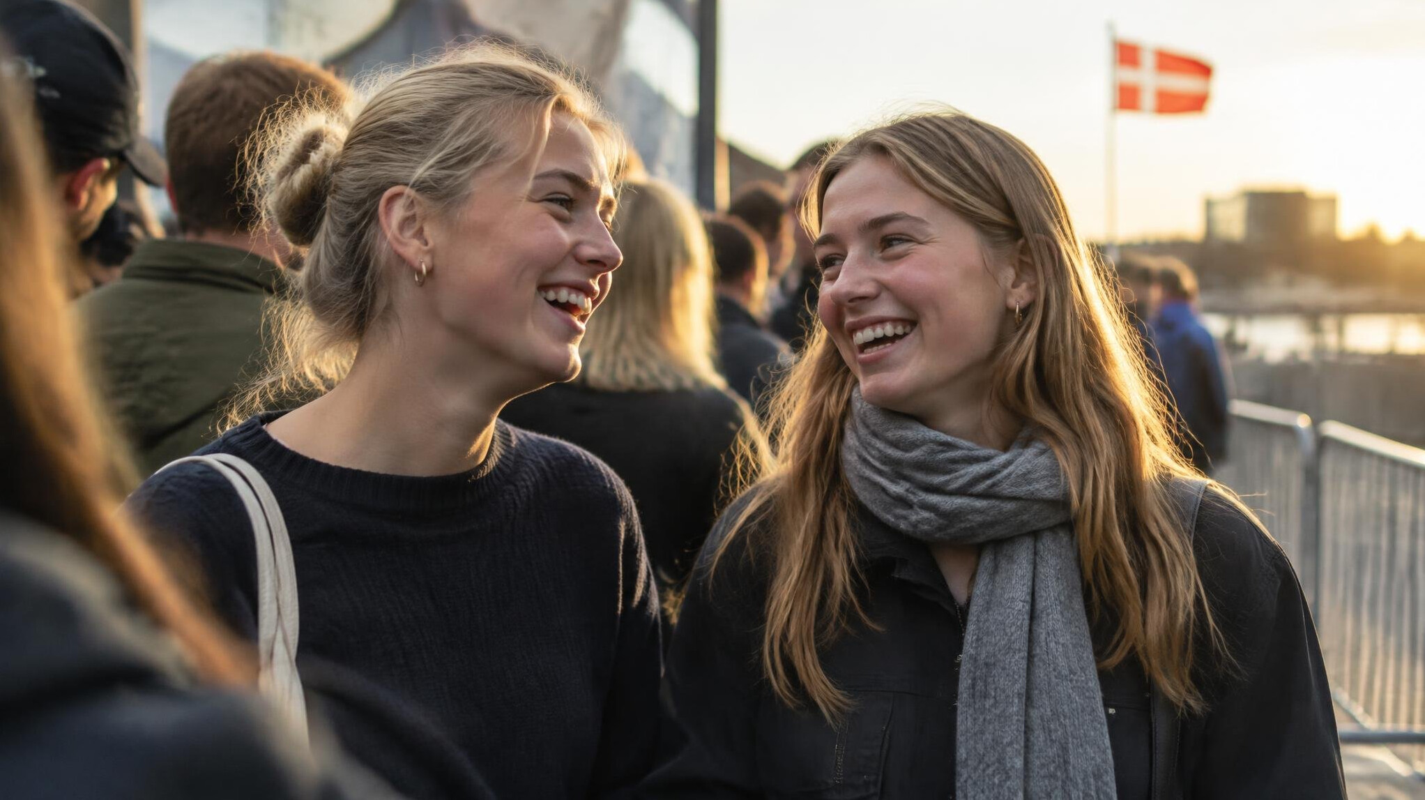 Two friends laughing together while waiting in a queue in Denmark