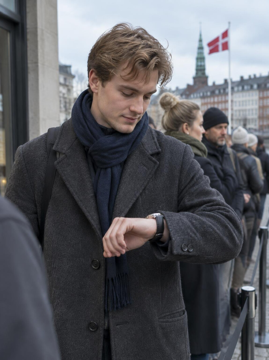 A young man checking his watch while waiting in a queue in Denmark